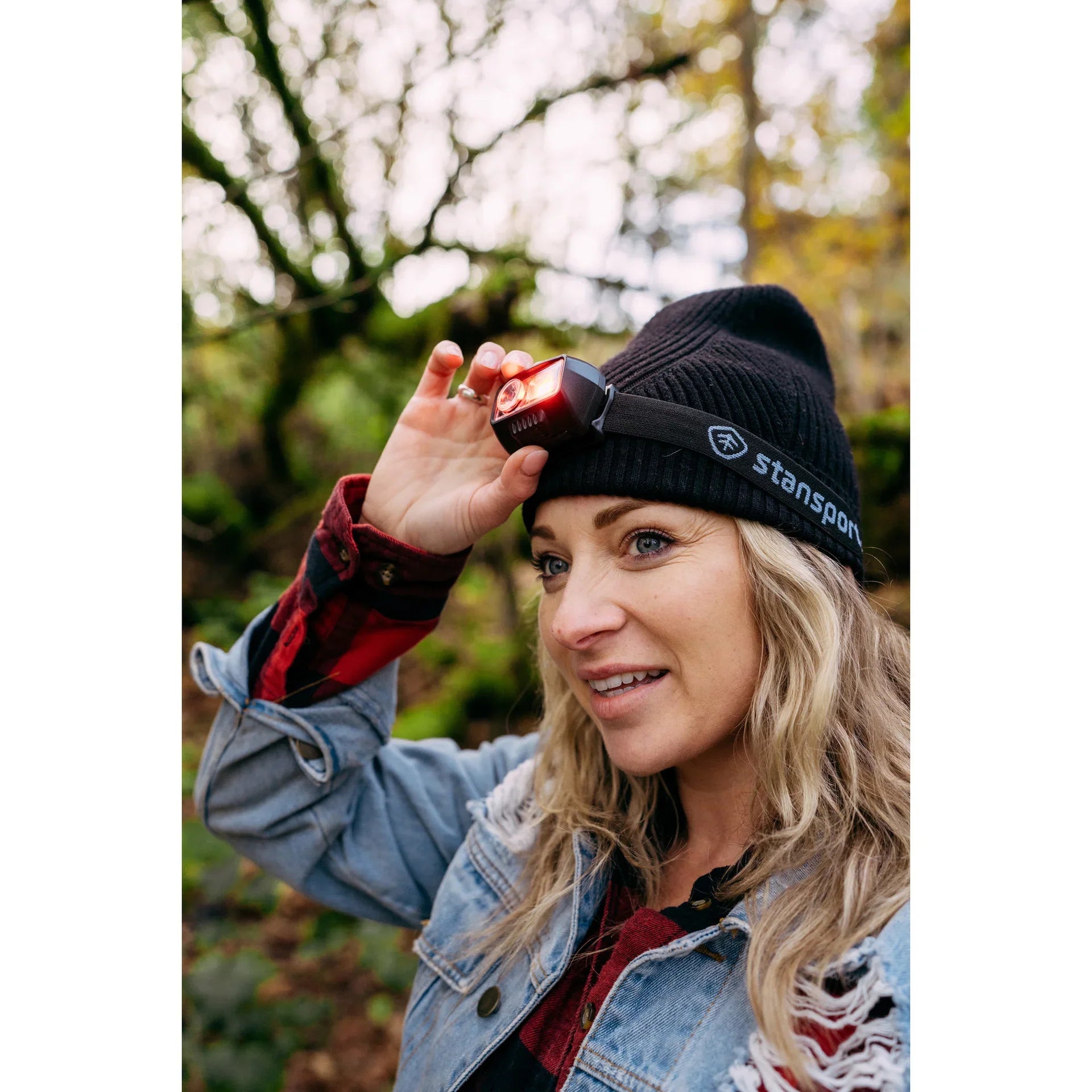 Woman outdoors wearing Stansport beanie and headlamp, forest background