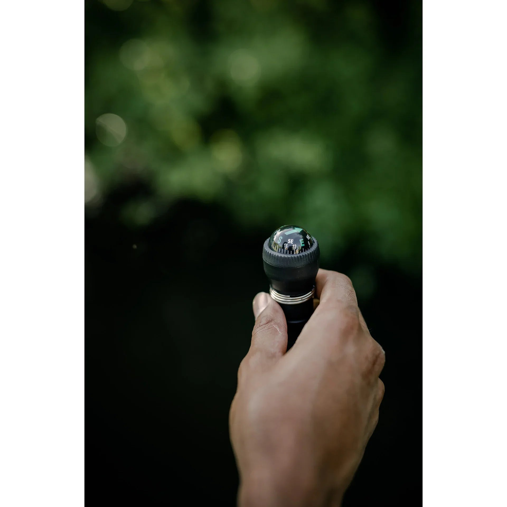 Hand holding trekking pole with built-in compass outdoors