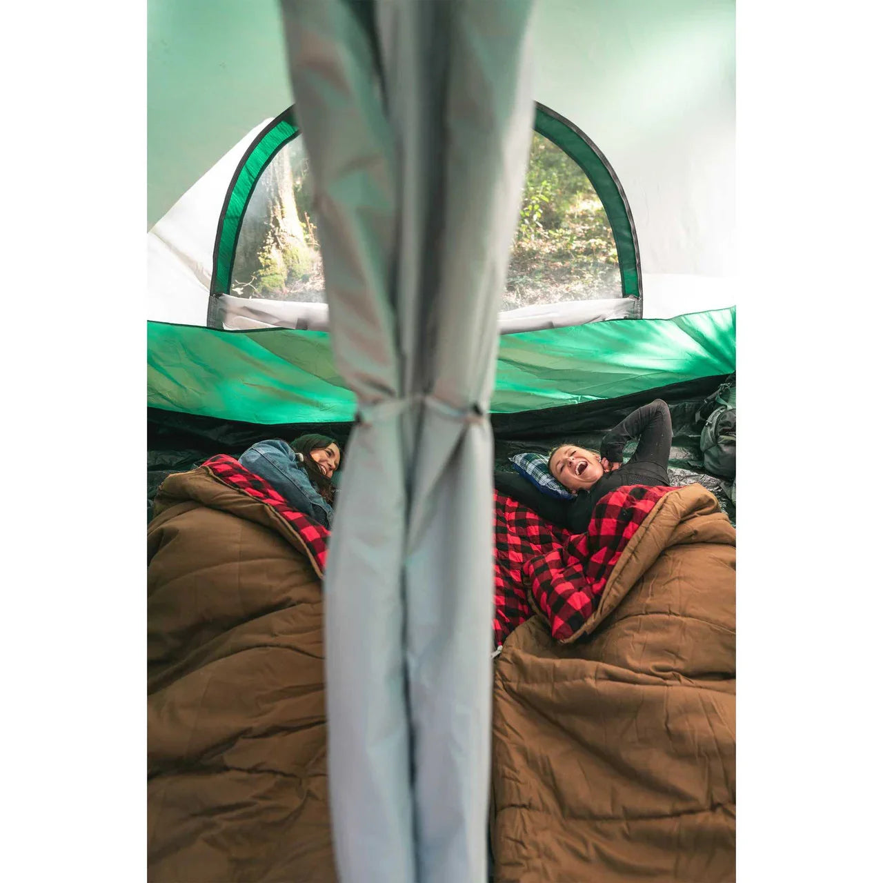 Two people in sleeping bags inside a tent, relaxing on camp pillows during camping trip