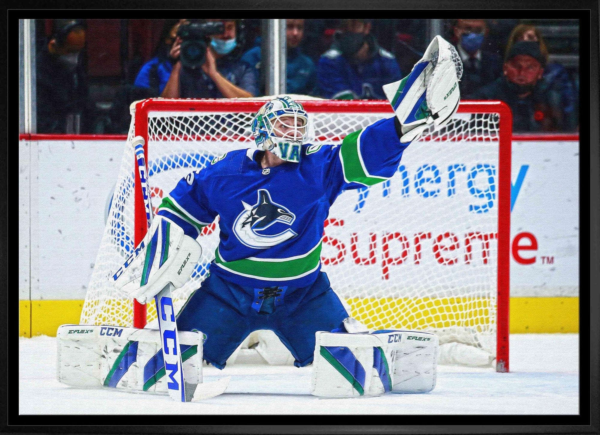 Vancouver Canucks goalie in blue uniform making a save in front of the hockey net