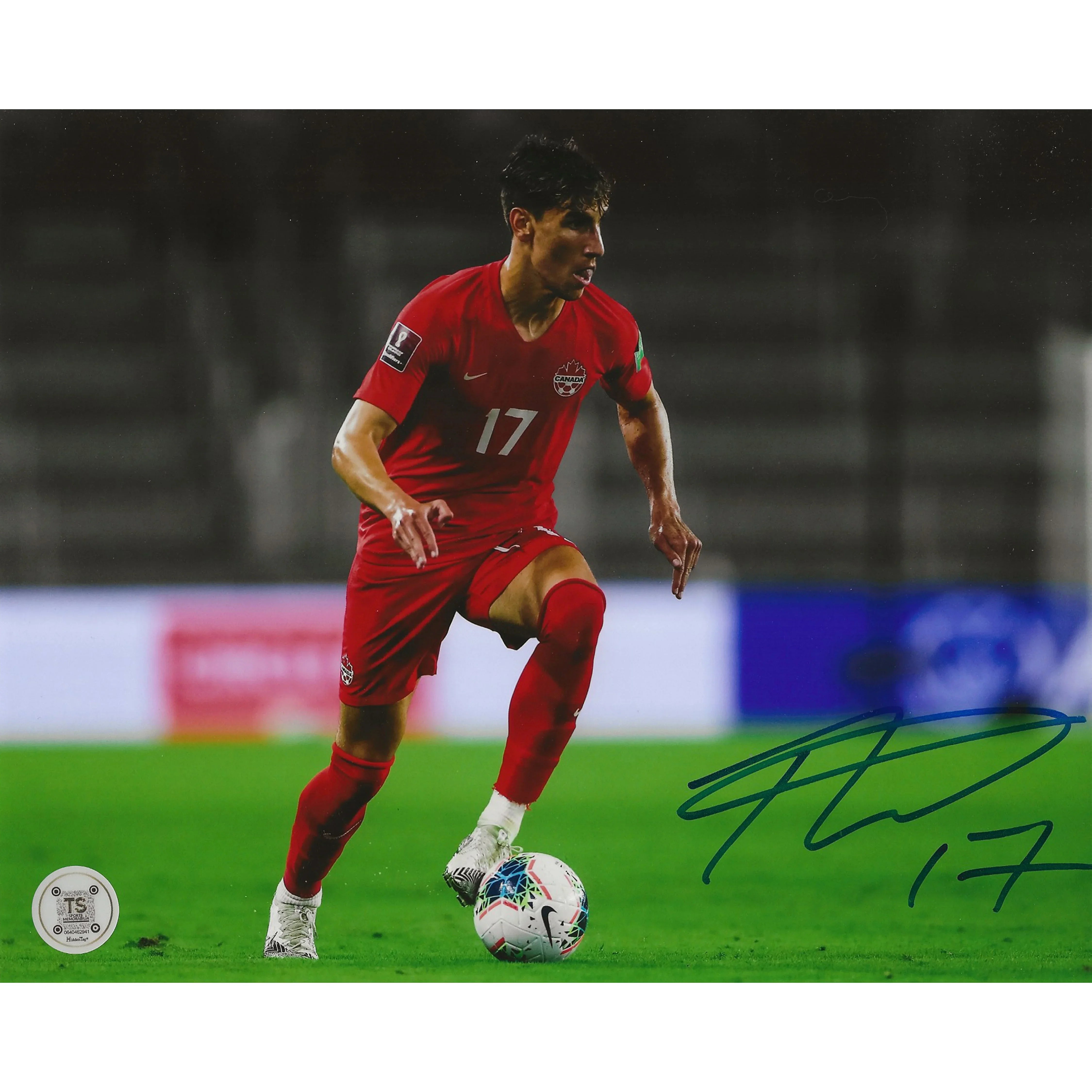 Canada soccer player in red jersey with number 17 dribbling ball on field, autograph visible