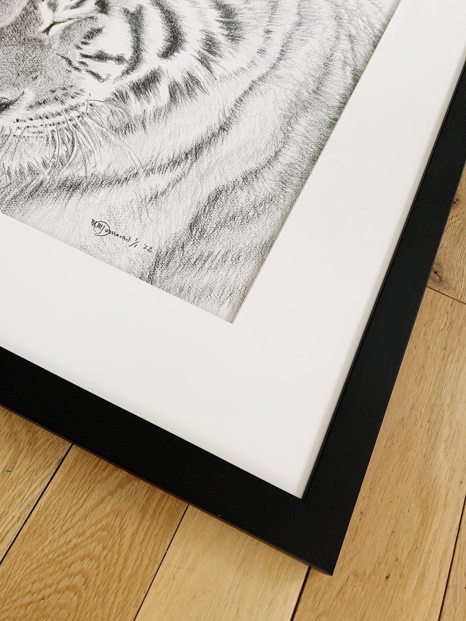 Framed black and white tiger illustration on wooden floor, close-up view