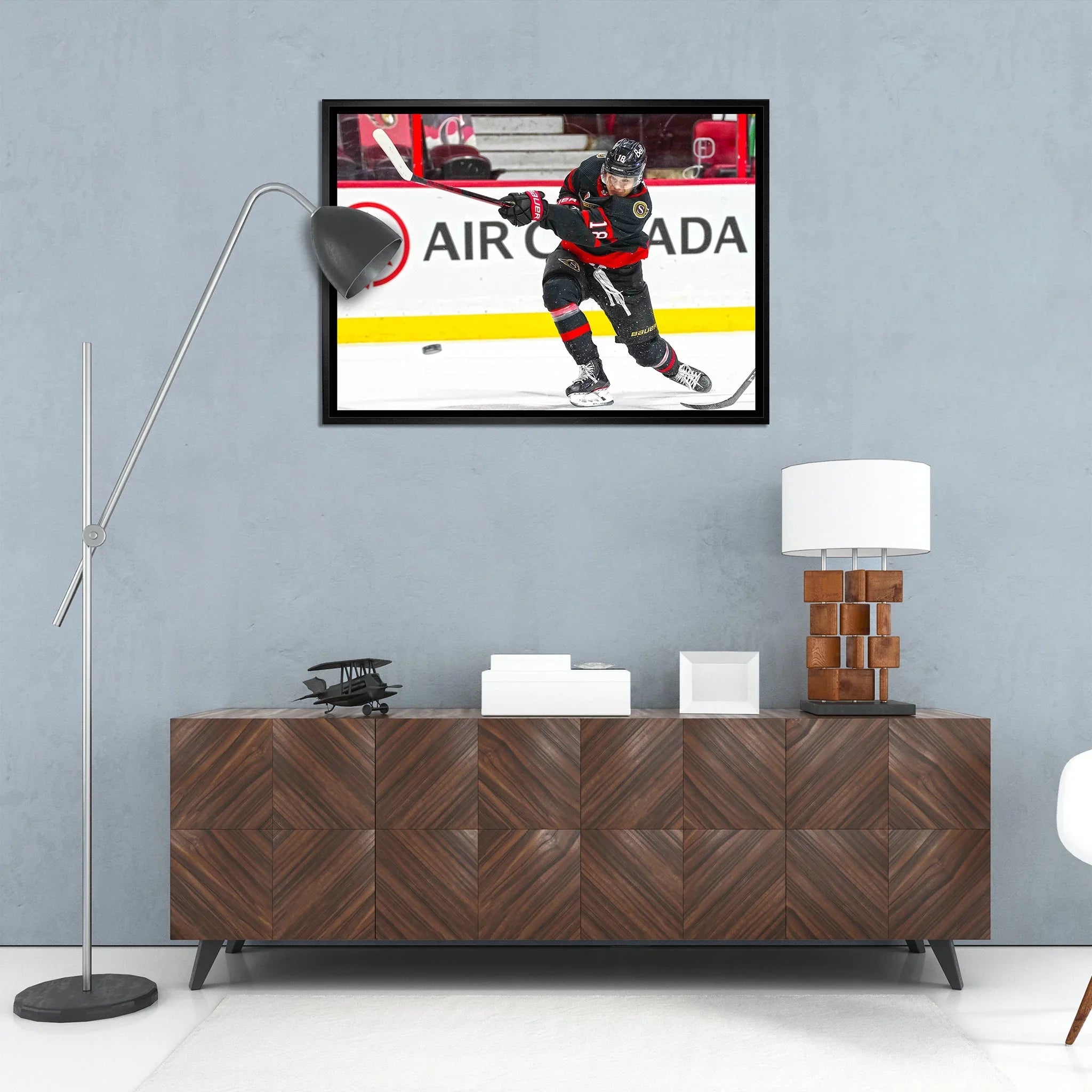 Modern living room with framed hockey player photo, wood cabinet, and floor lamp