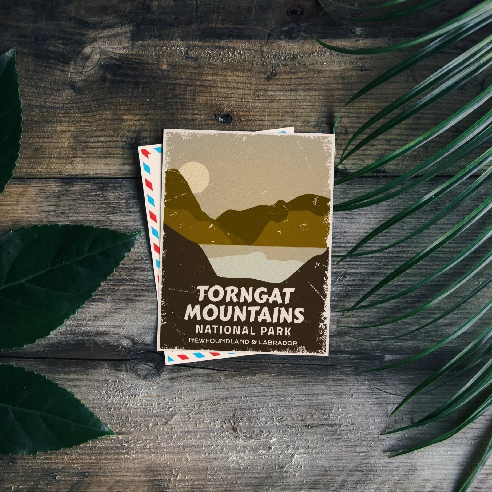 Torngat Mountains National Park postcard on wooden table with green leaves, vintage design