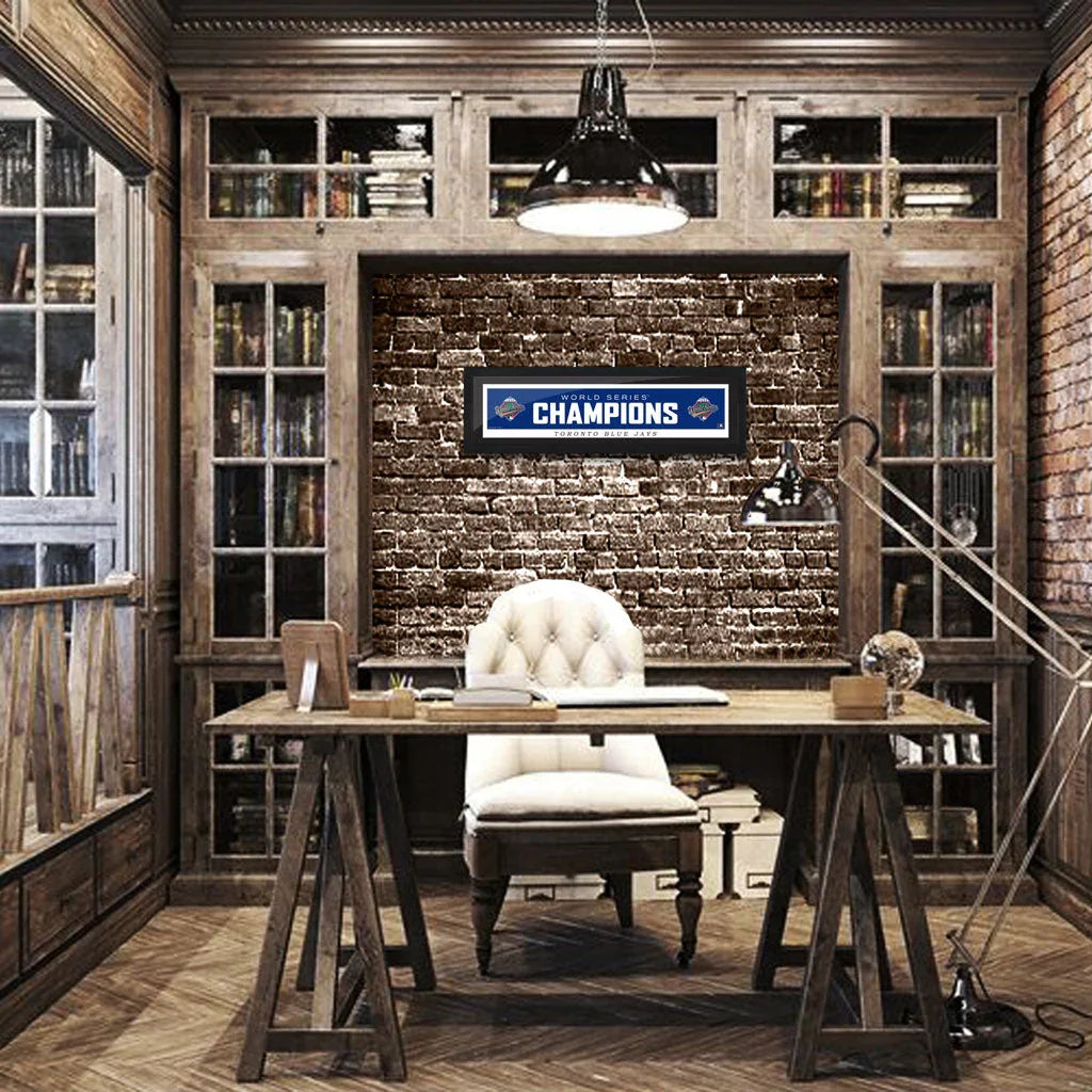 Rustic office with wooden desk, tufted chair, Toronto Blue Jays World Series Champions sign on brick wall