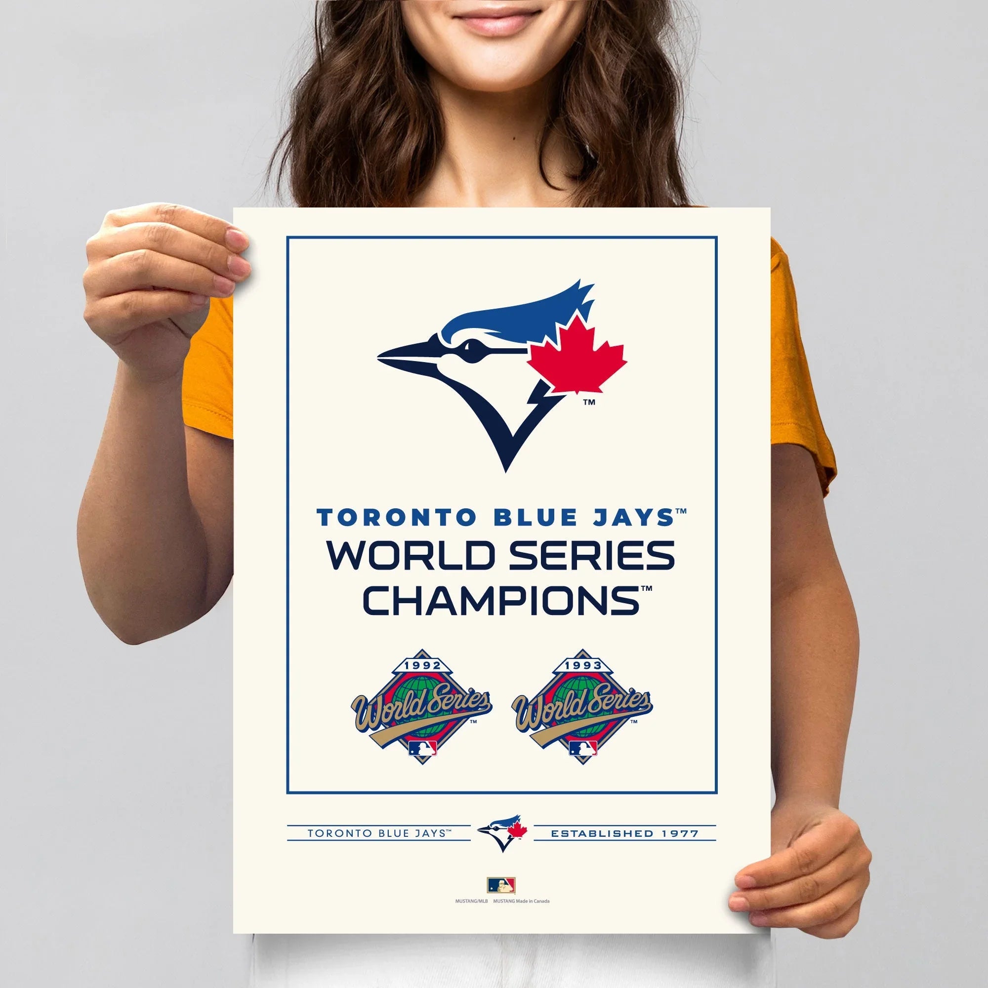 Woman holding Toronto Blue Jays World Series Champions poster with team logo and championship years.