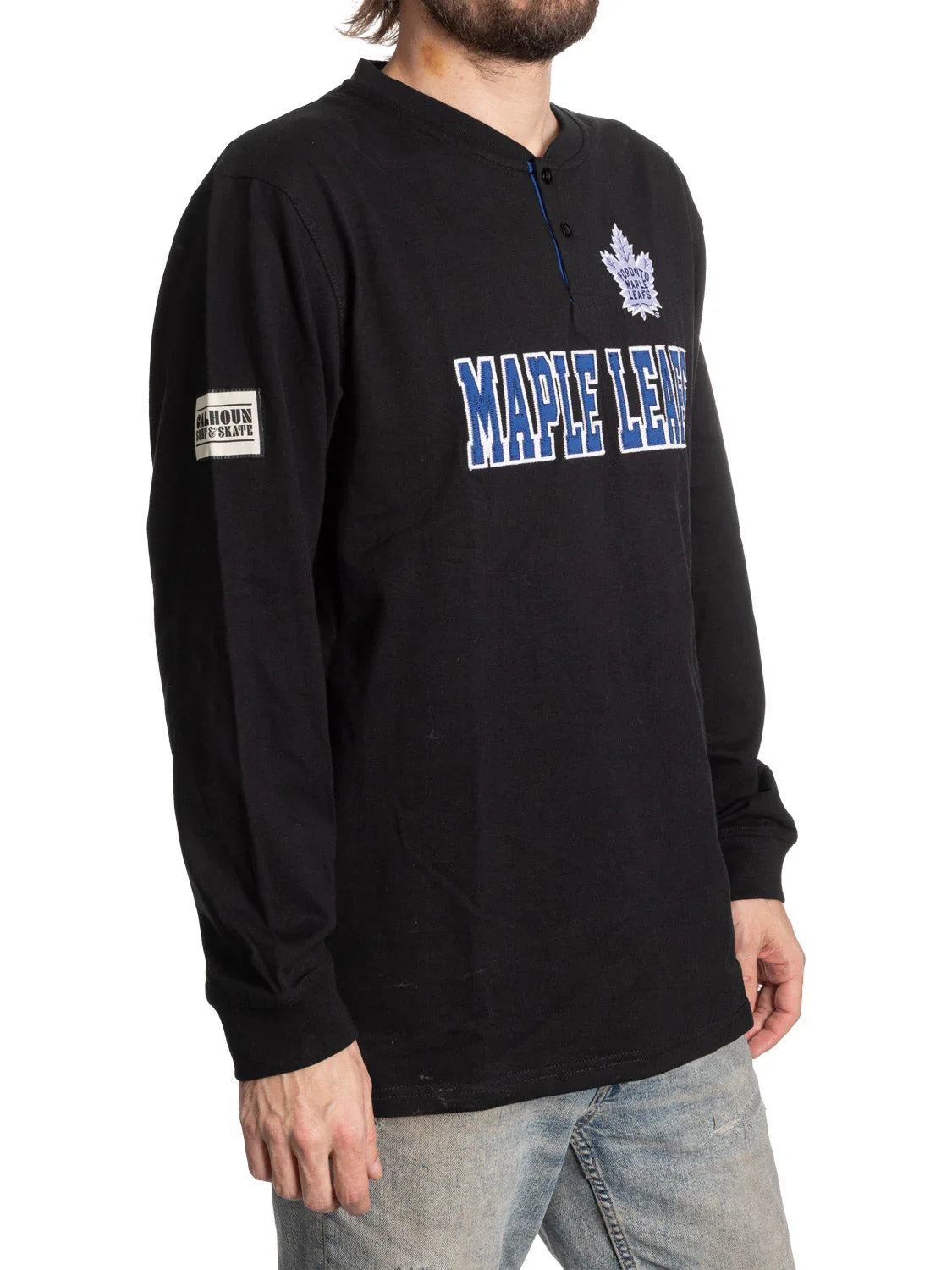 Man wearing black Toronto Maple Leafs henley shirt with long sleeves and denim jeans