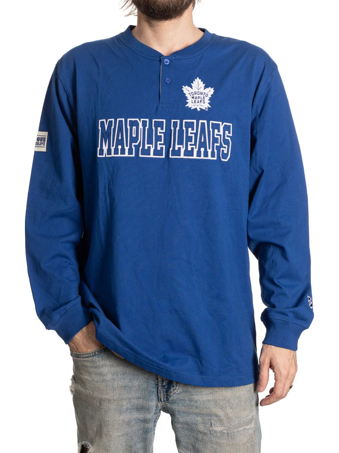 Man wearing blue Toronto Maple Leafs long sleeve henley shirt and distressed jeans