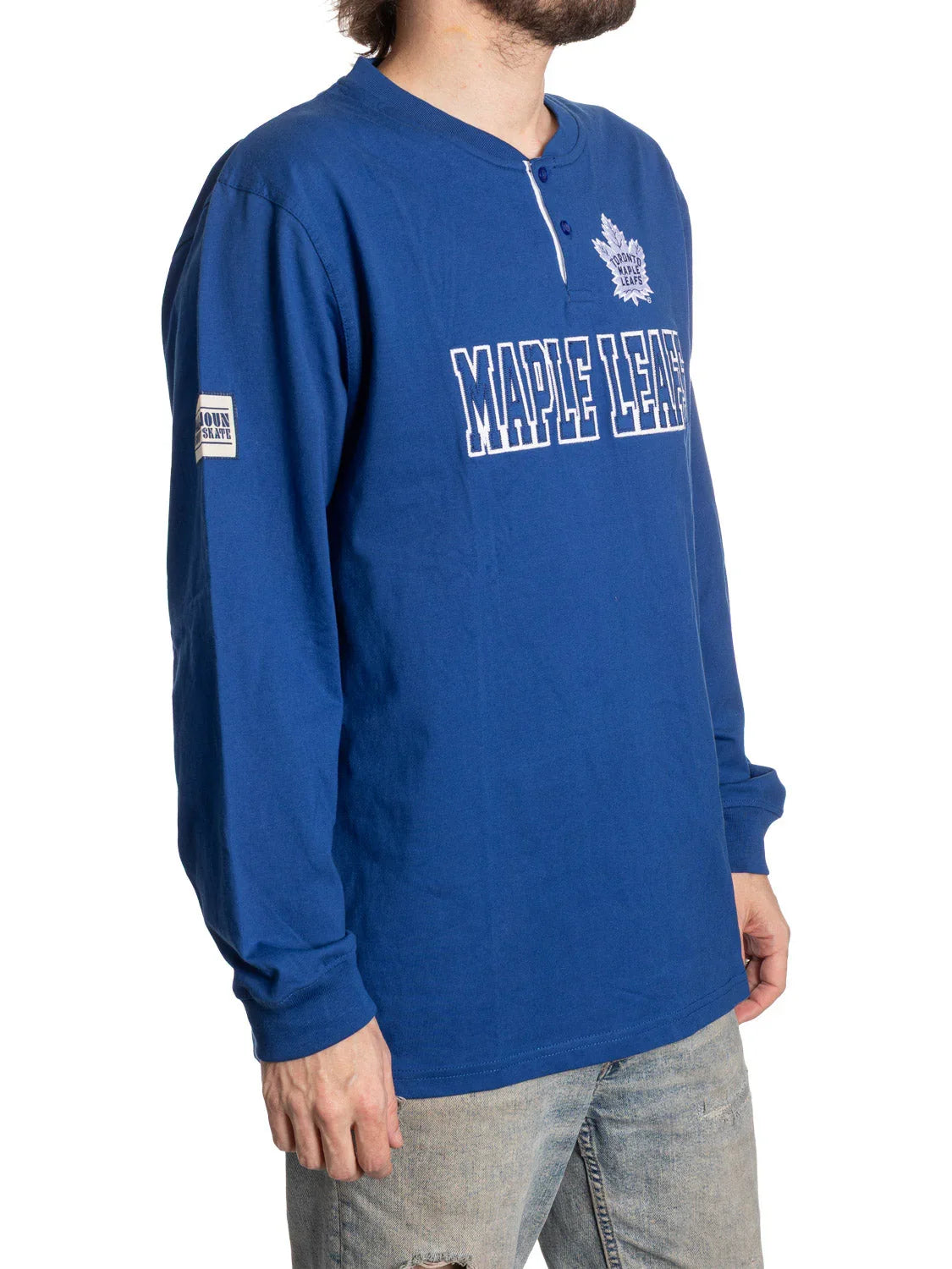 Man wearing blue Toronto Maple Leafs long sleeve henley shirt and light jeans
