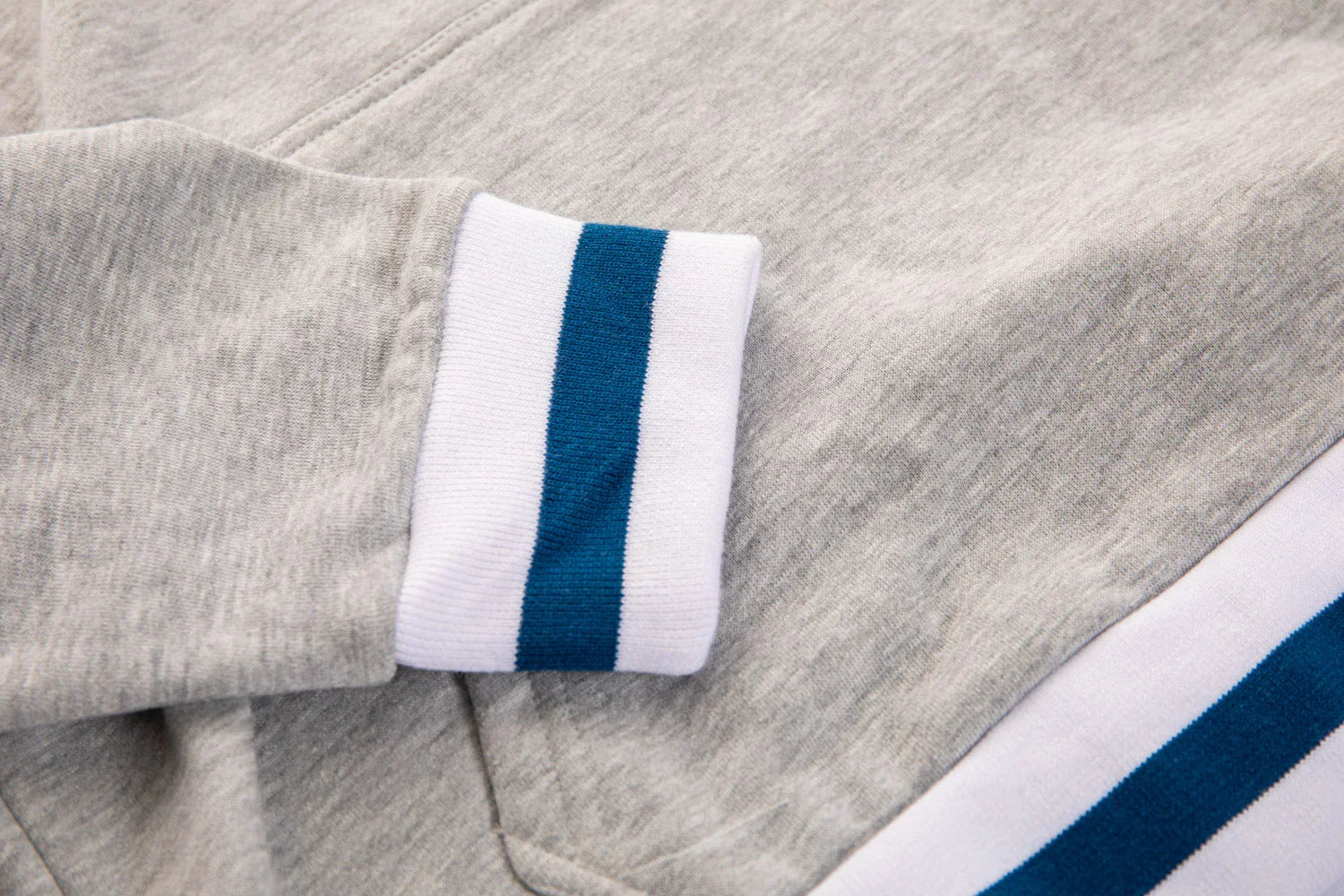 Light grey sweatshirt cuff with white and blue stripe detail, close-up fabric texture
