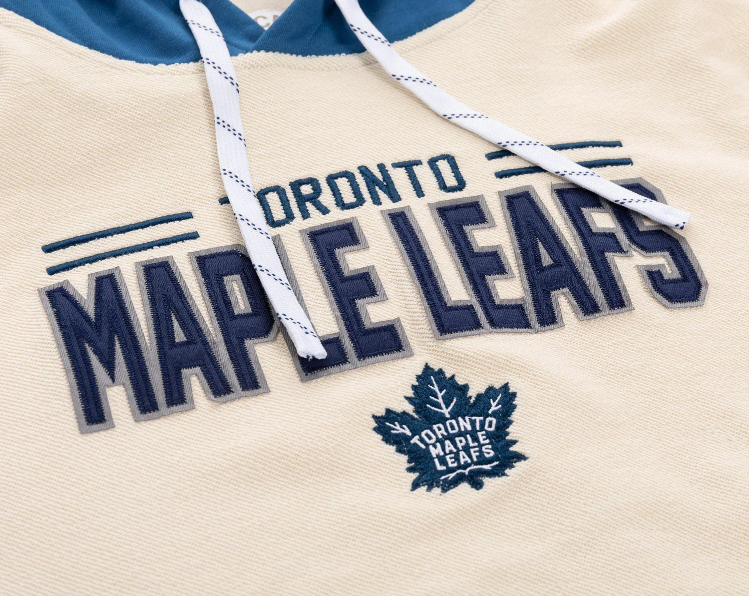 Toronto Maple Leafs hoodie detail with embroidered logo and drawstrings on cream fabric