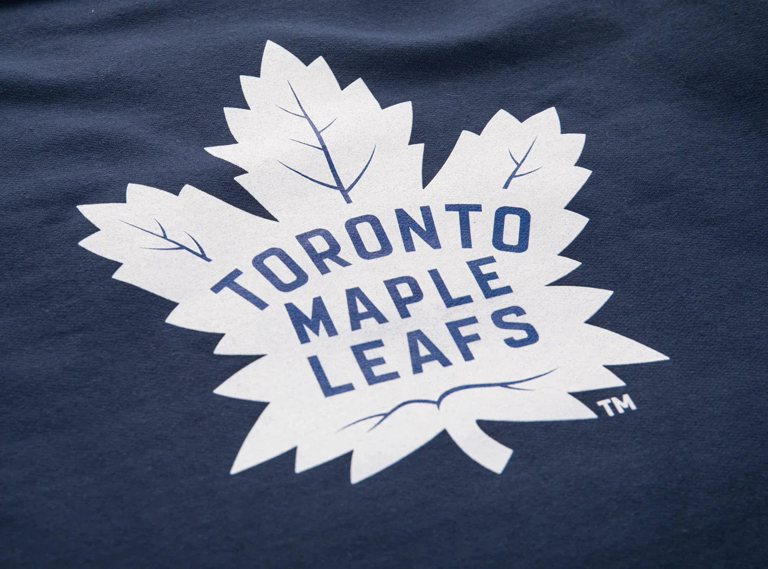 Toronto Maple Leafs logo on navy blue varsity sweater fabric