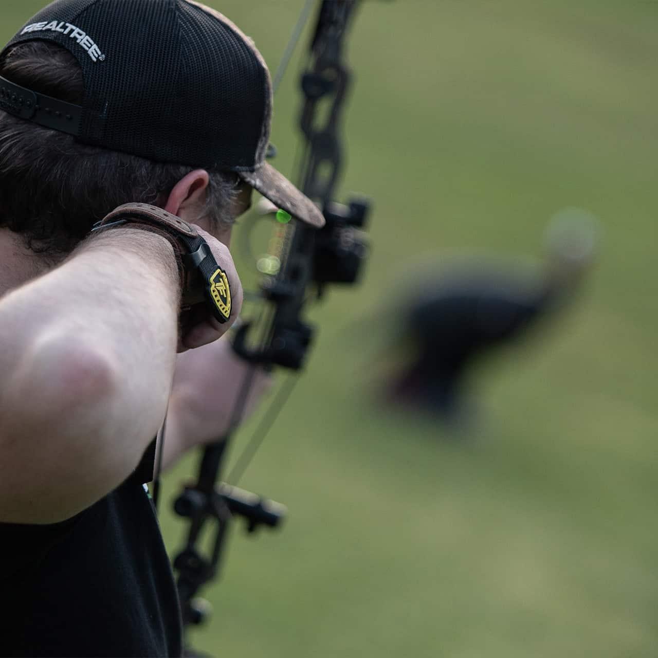 Archer using Trufire archery release aid with compound bow outdoors, Realtree cap visible