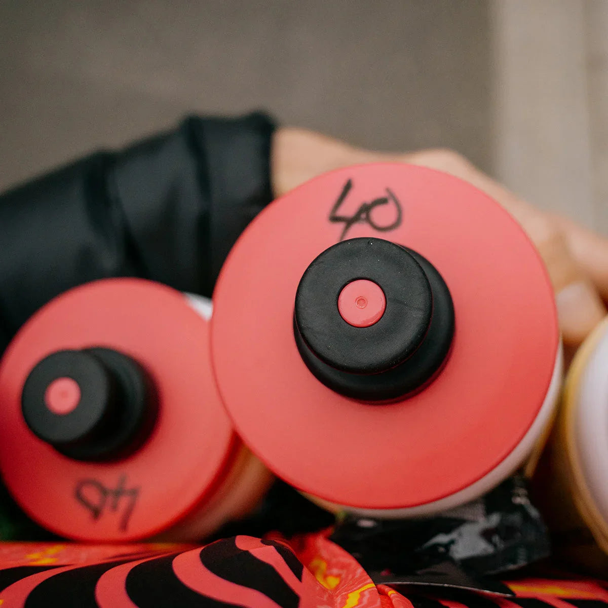 close-up of red sport water bottles with black numbers, hand in black sleeve visible