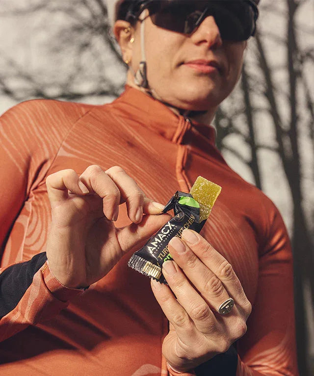 Cyclist in orange jersey holding MAURTEN Turbofrutichew citrus energy chew outdoors