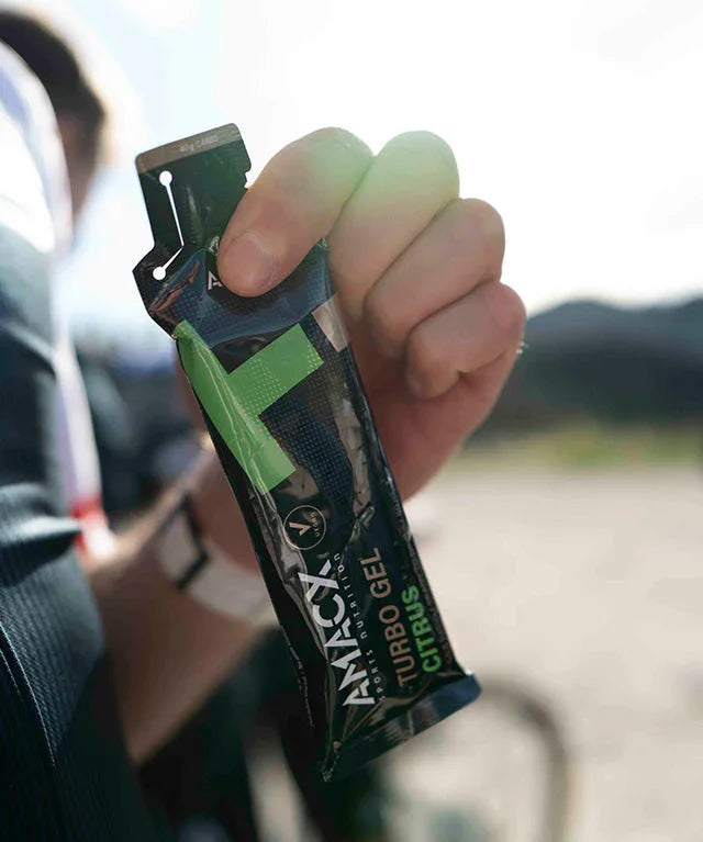 Hand holding Attack Turbo Gel Citrus energy gel outdoors in sunlight