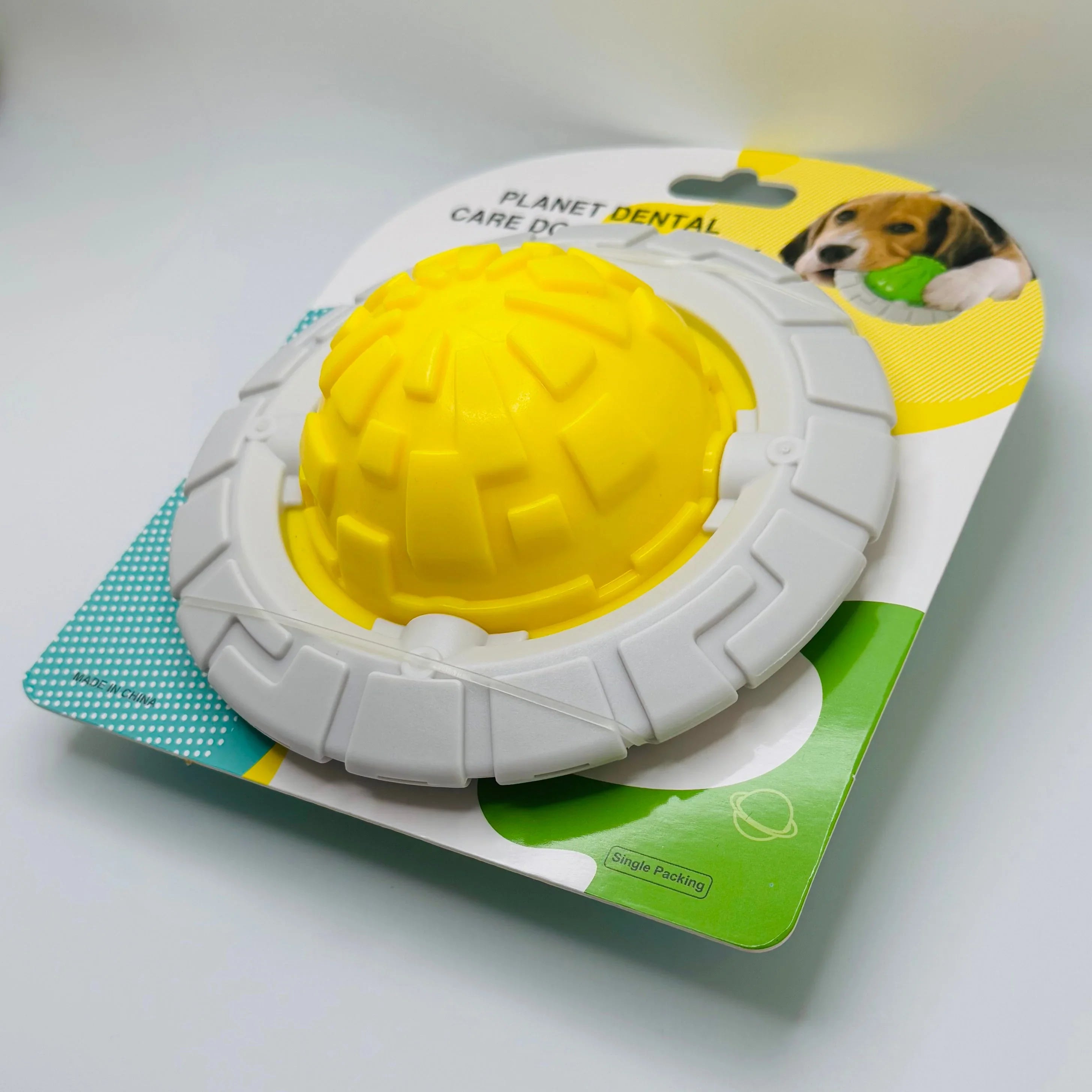 Yellow and gray planet-shaped dog dental toy in packaging with a dog photo on the label