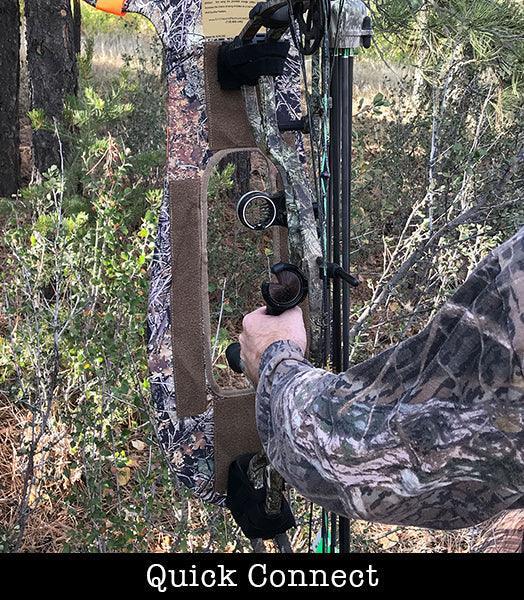 Hunter attaching camo stalker decoy to compound bow in wooded outdoor setting