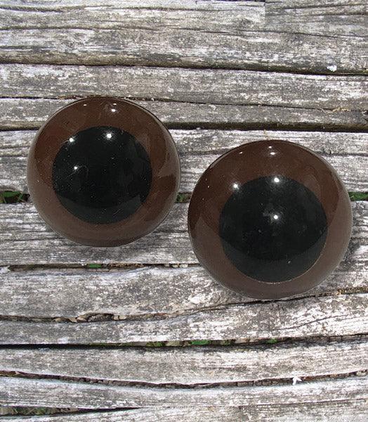 Pair of round decoy eyes with dark pupils on weathered wooden surface outdoors