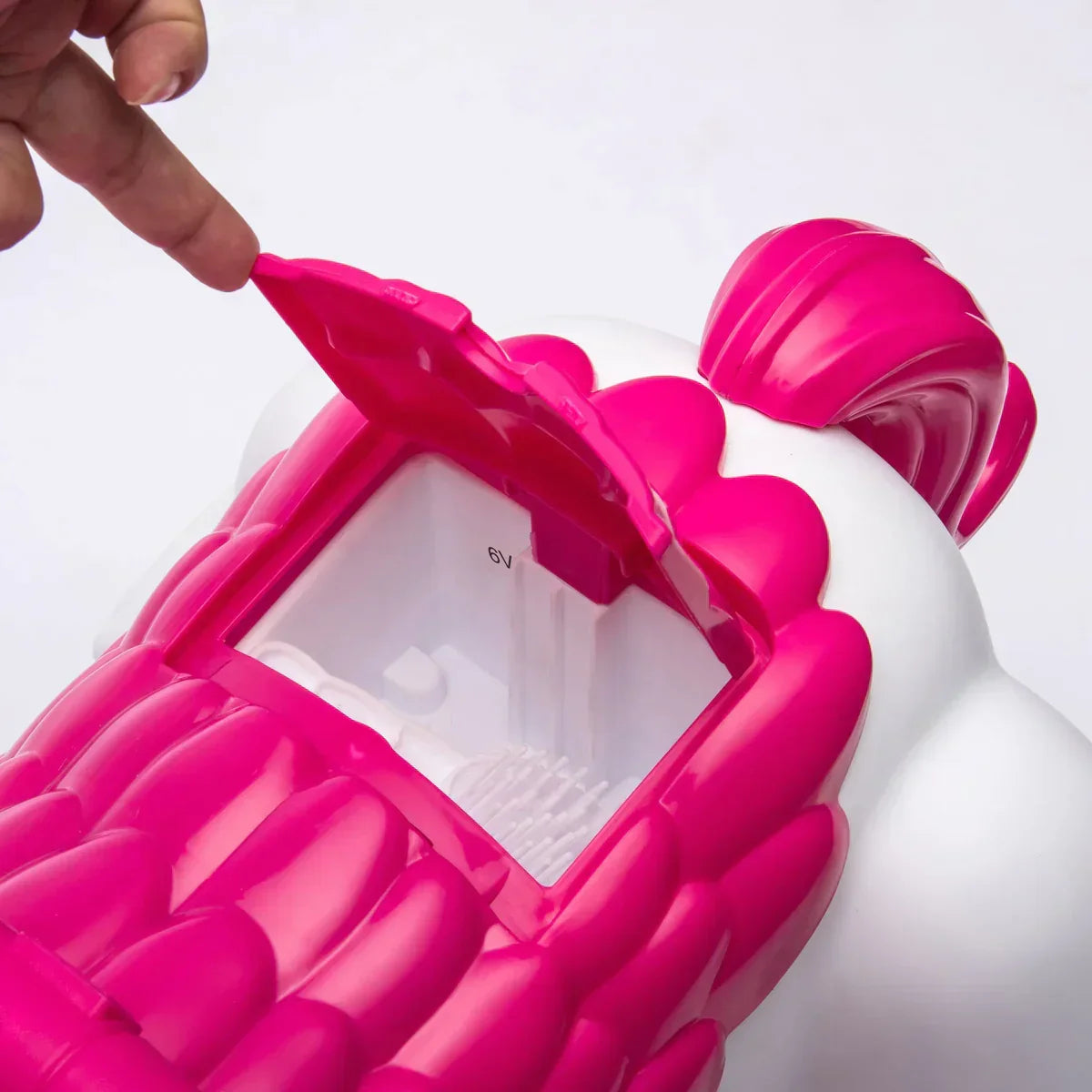 Close-up of pink and white unicorn toy battery compartment being opened by a hand