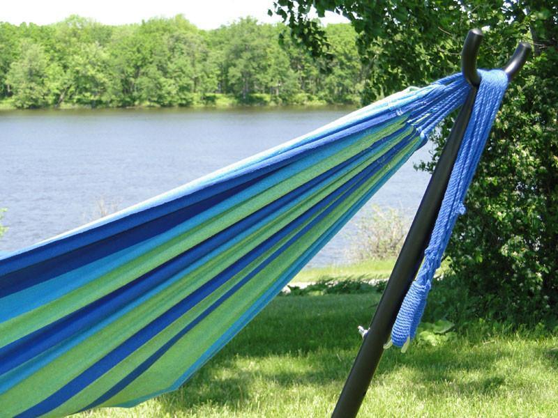 Universal hammock stand with blue striped hammock by a lake in a grassy outdoor setting
