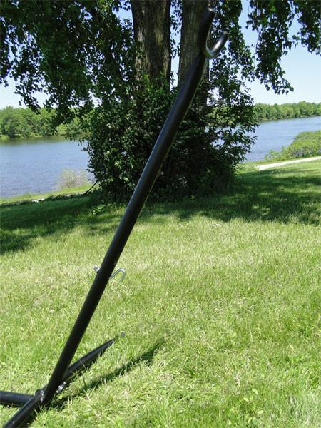 Black universal hammock stand on green grass near trees and a lake