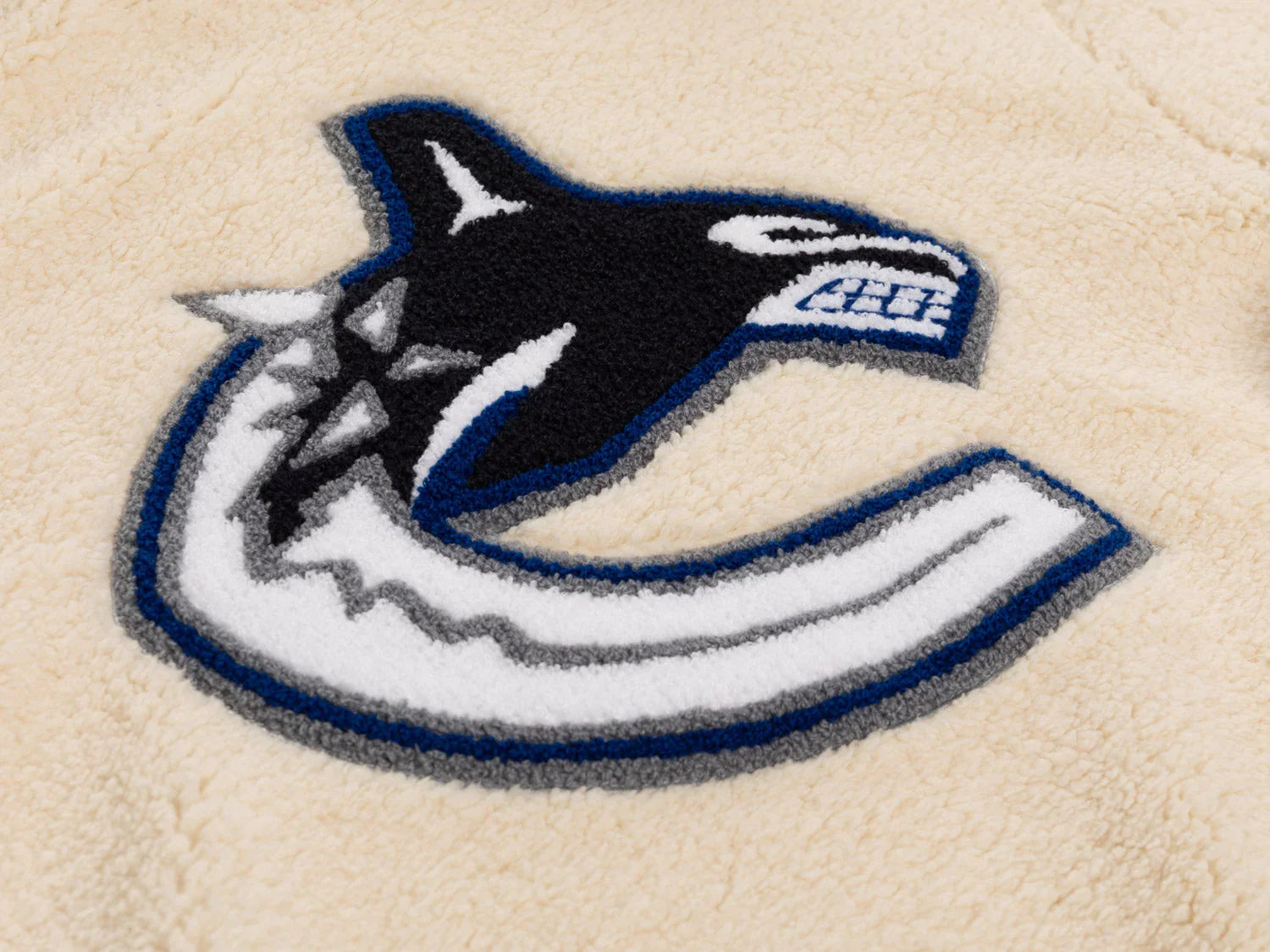 Vancouver Canucks orca logo embroidered on beige sherpa fleece fabric