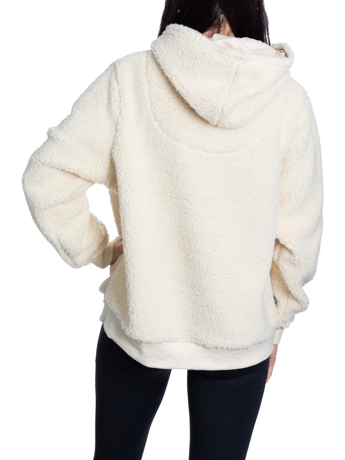 Back view of woman wearing an ivory sherpa fleece hoodie and black leggings