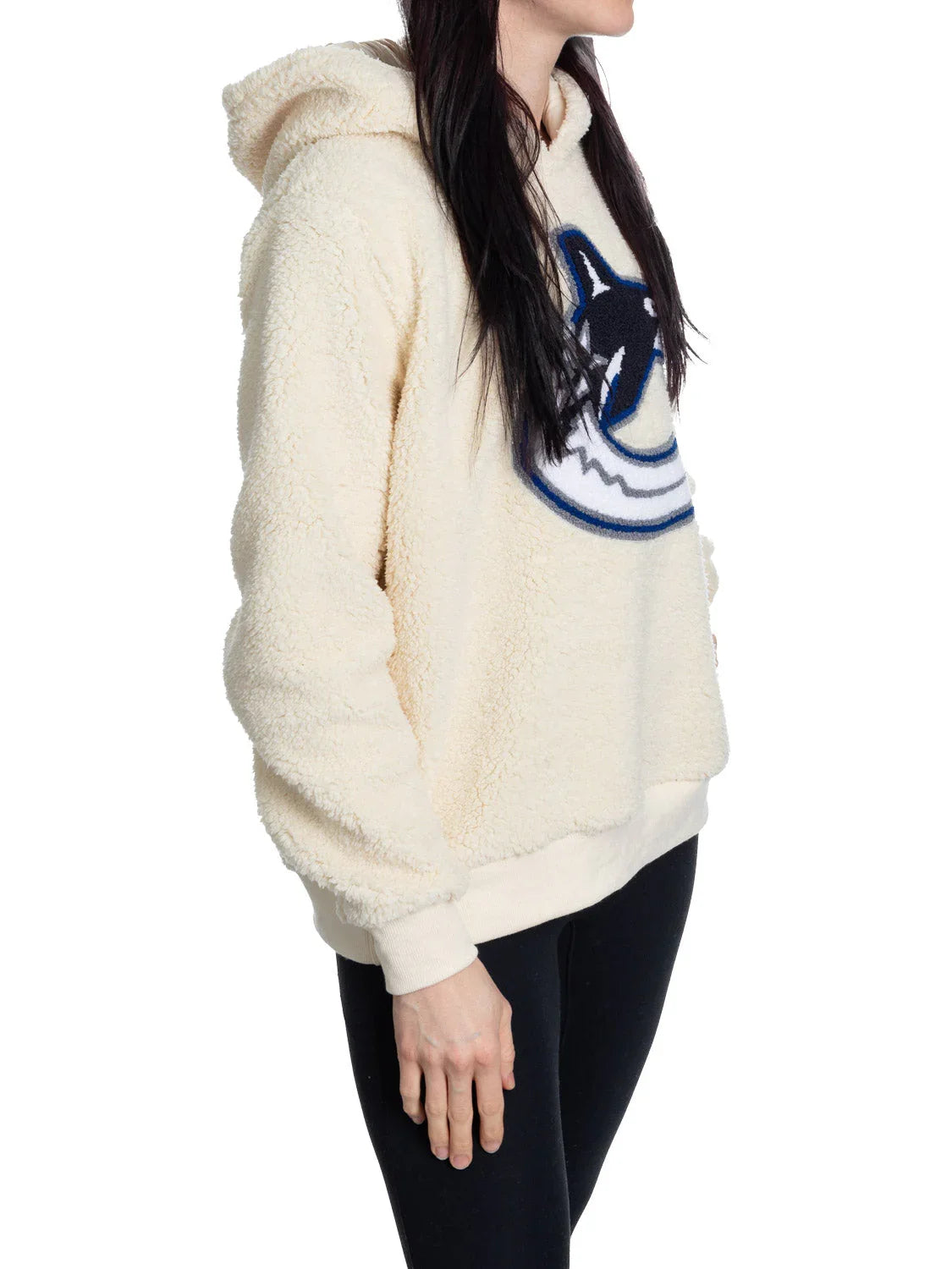 Woman wearing cream Vancouver Canucks sherpa hoodie with orca logo, side view