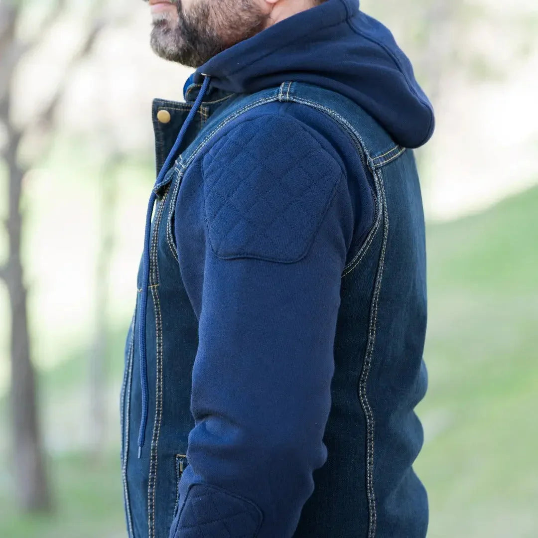Man wearing a blue denim vest with hoodie and quilted sleeves outdoors
