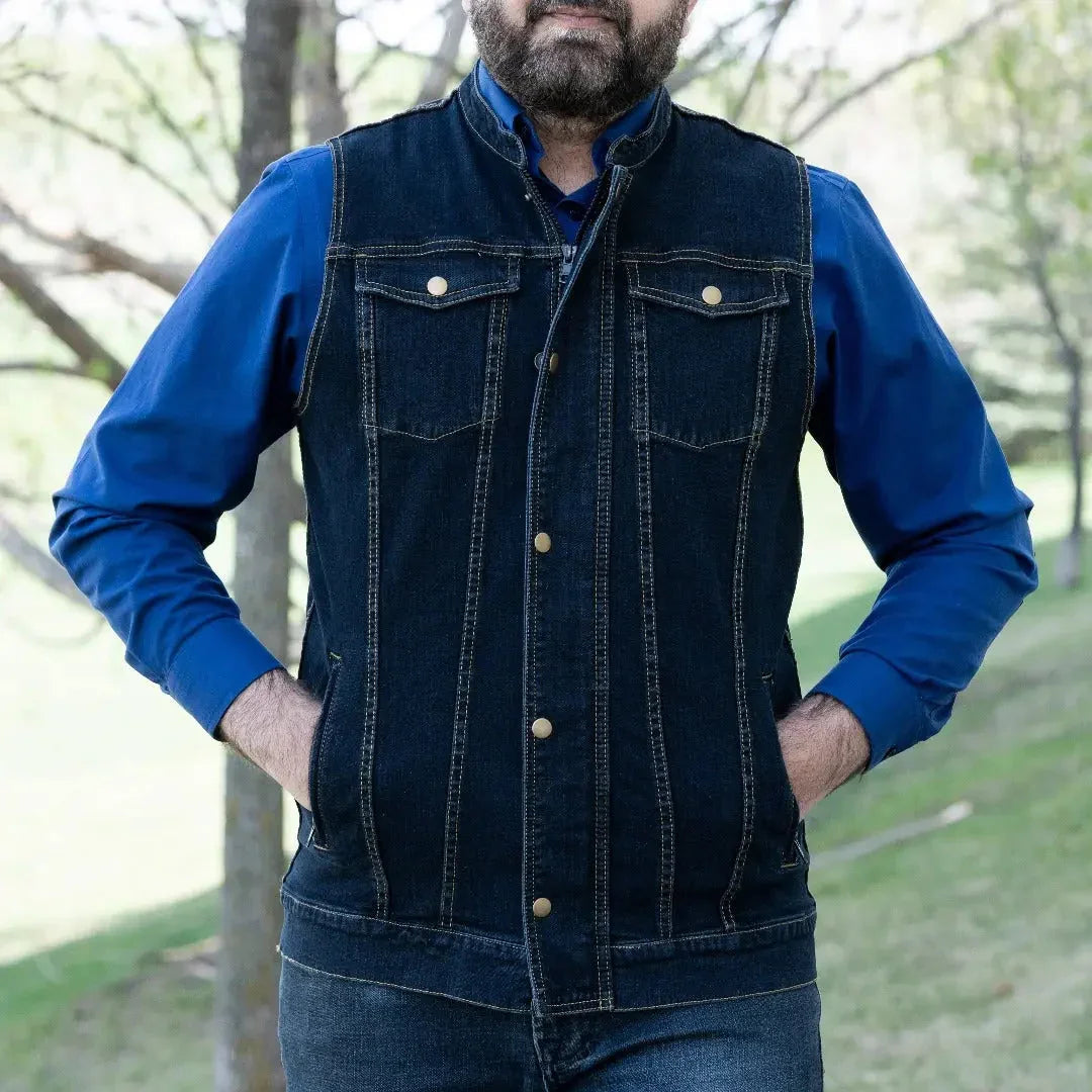 Man wearing dark blue denim vest over blue shirt, outdoors in a park setting