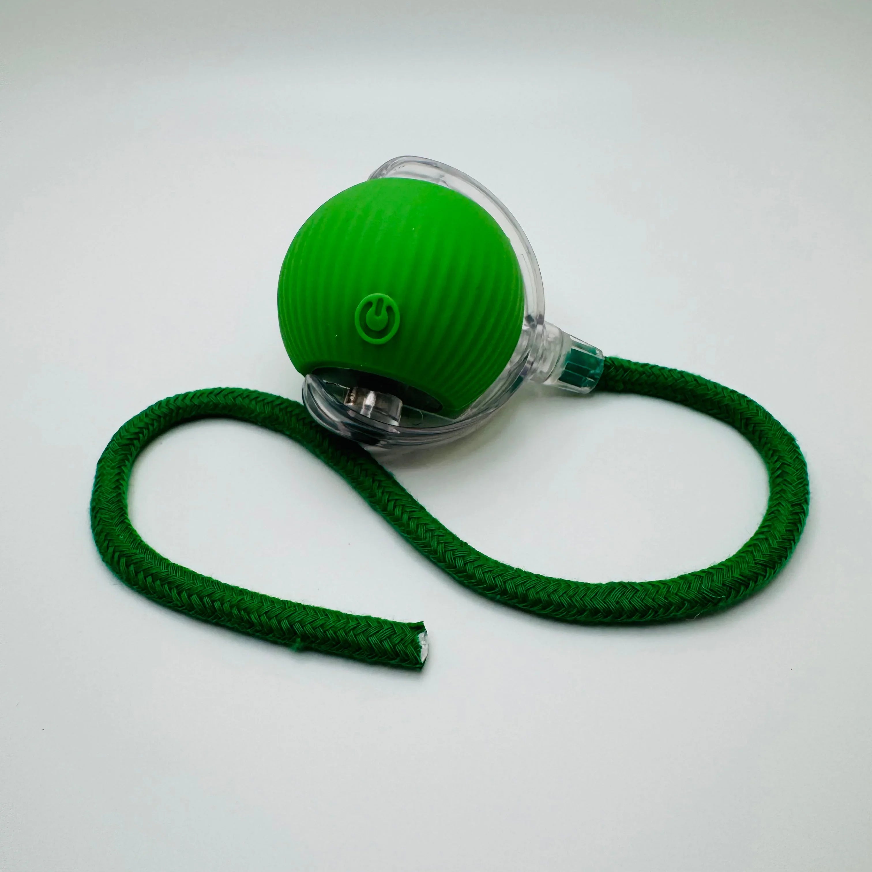 Green pet ball toy with power button, braided green rope on white background