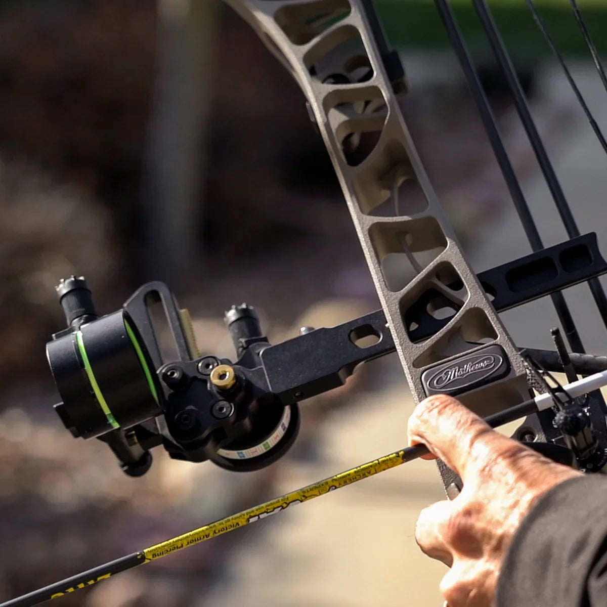 Close-up of archer drawing a Mathews compound bow with a Victory VAP arrow outdoors