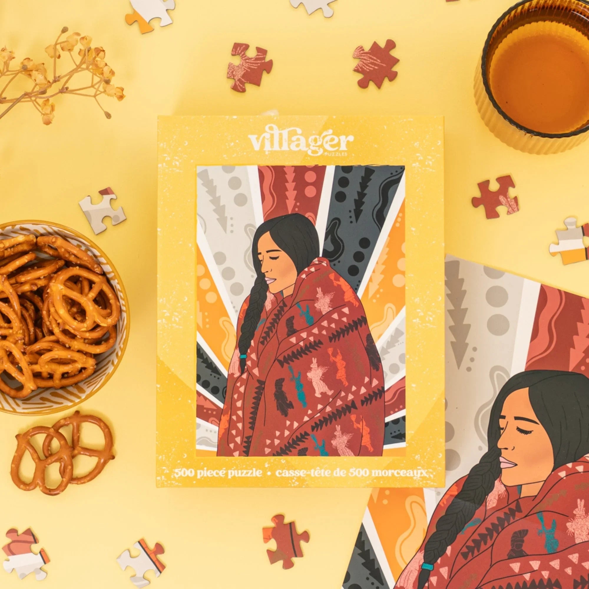 500-piece puzzle box with illustrated woman in a patterned blanket, pretzels, and puzzle pieces