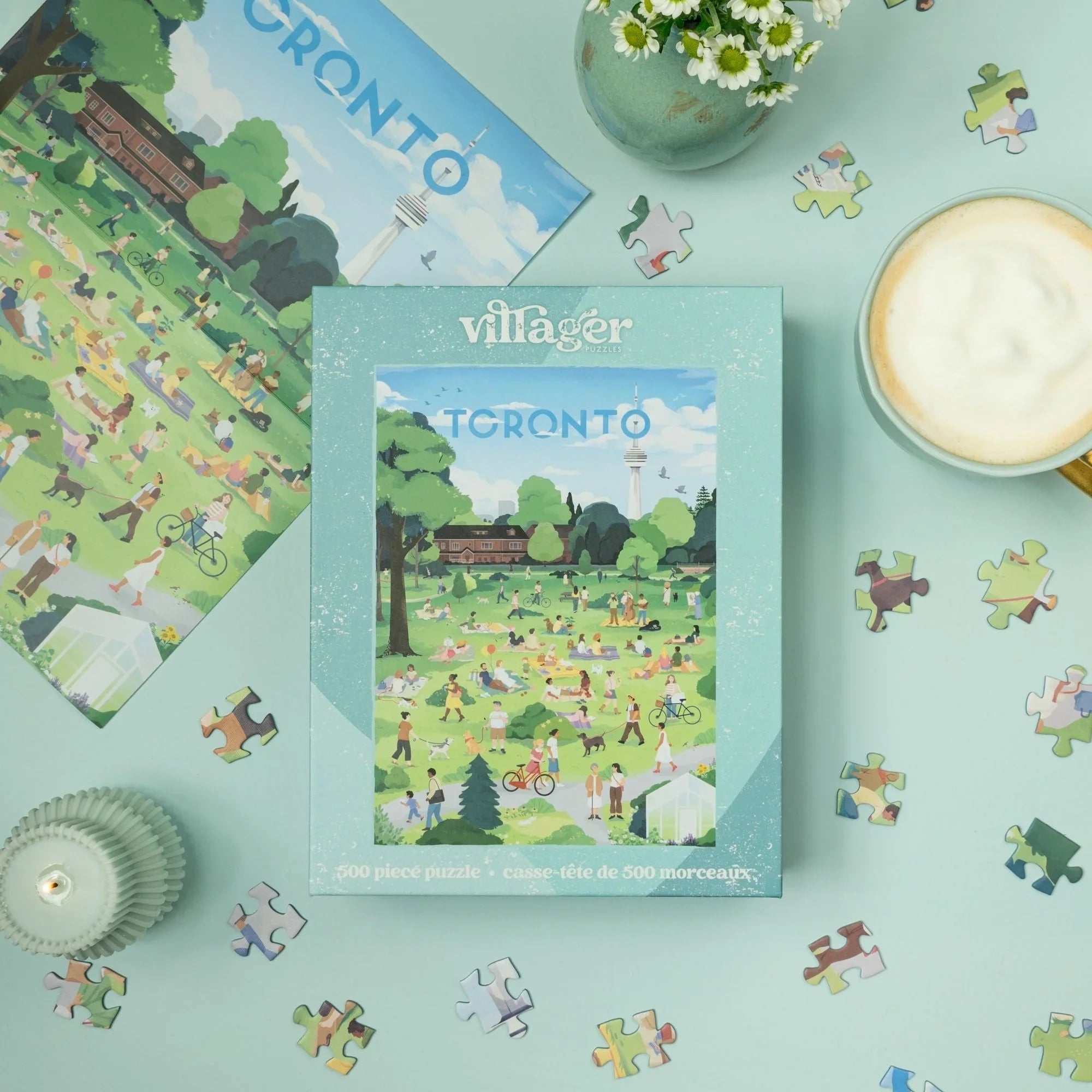 Toronto park 500-piece puzzle box with scattered pieces, coffee, and flowers on table