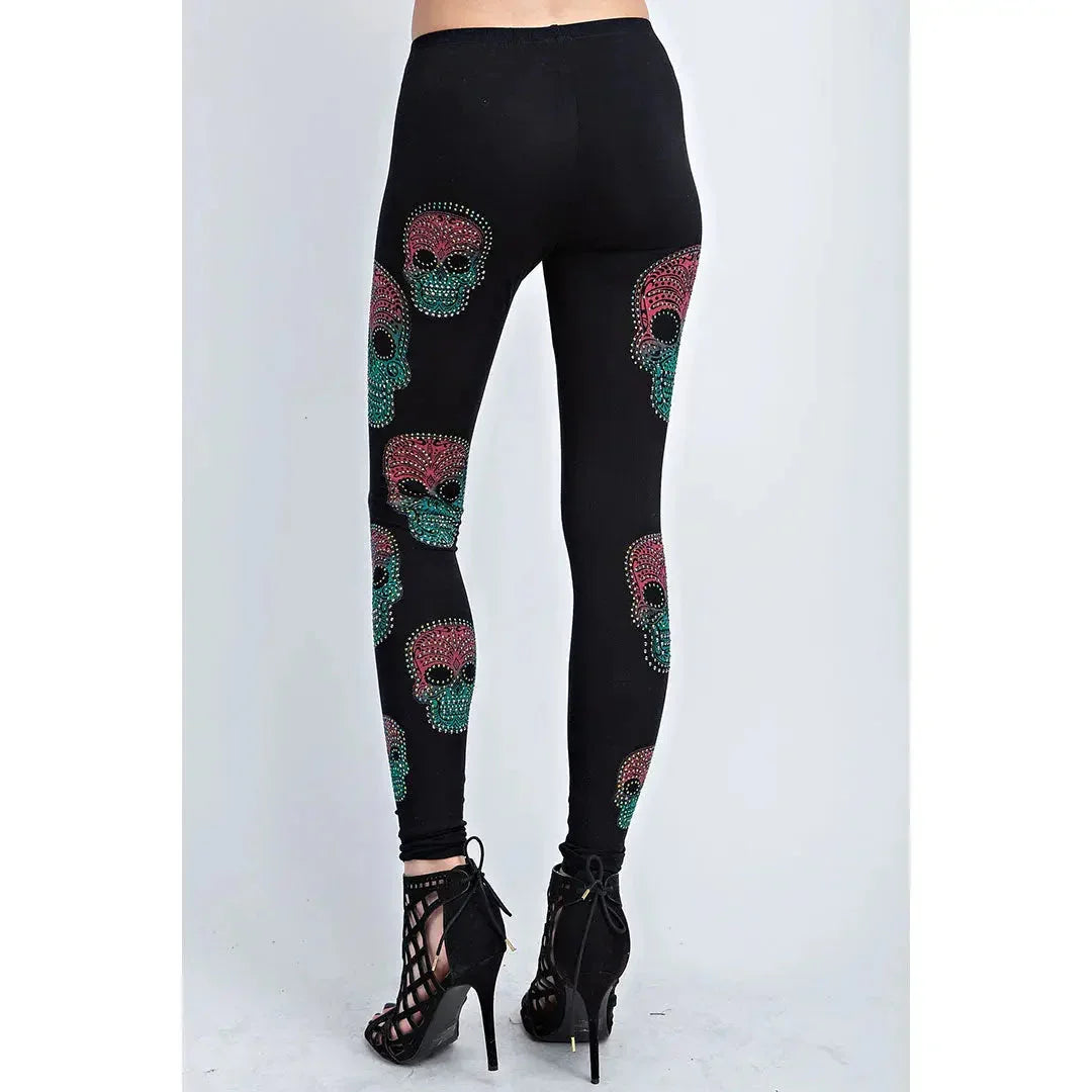 Woman wearing black sugar skull leggings with red and green skull prints, high heels