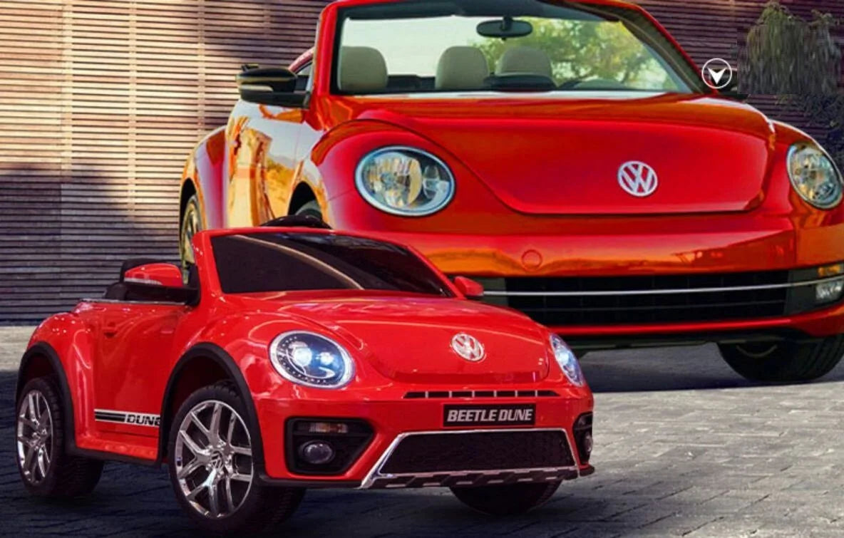 Red Volkswagen Beetle Dune ride-on toy car in front of a full-size red VW Beetle convertible