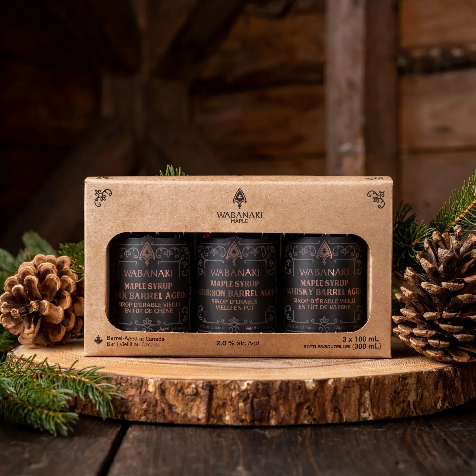 Wabanaki maple syrup gift set with pinecones and greenery on rustic wooden background