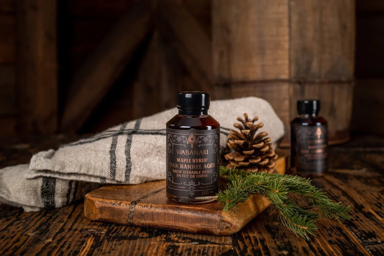 Wabanaki maple syrup oak barrel aged bottle on rustic wood with pinecone and fir sprig