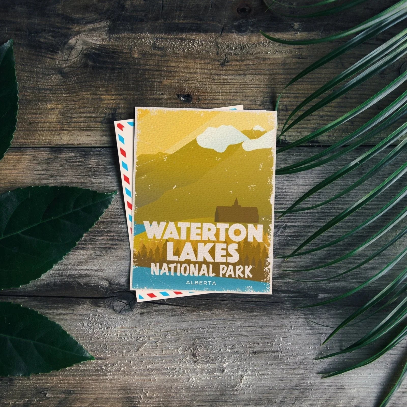 Waterton Lakes National Park postcard on rustic wood with green leaves