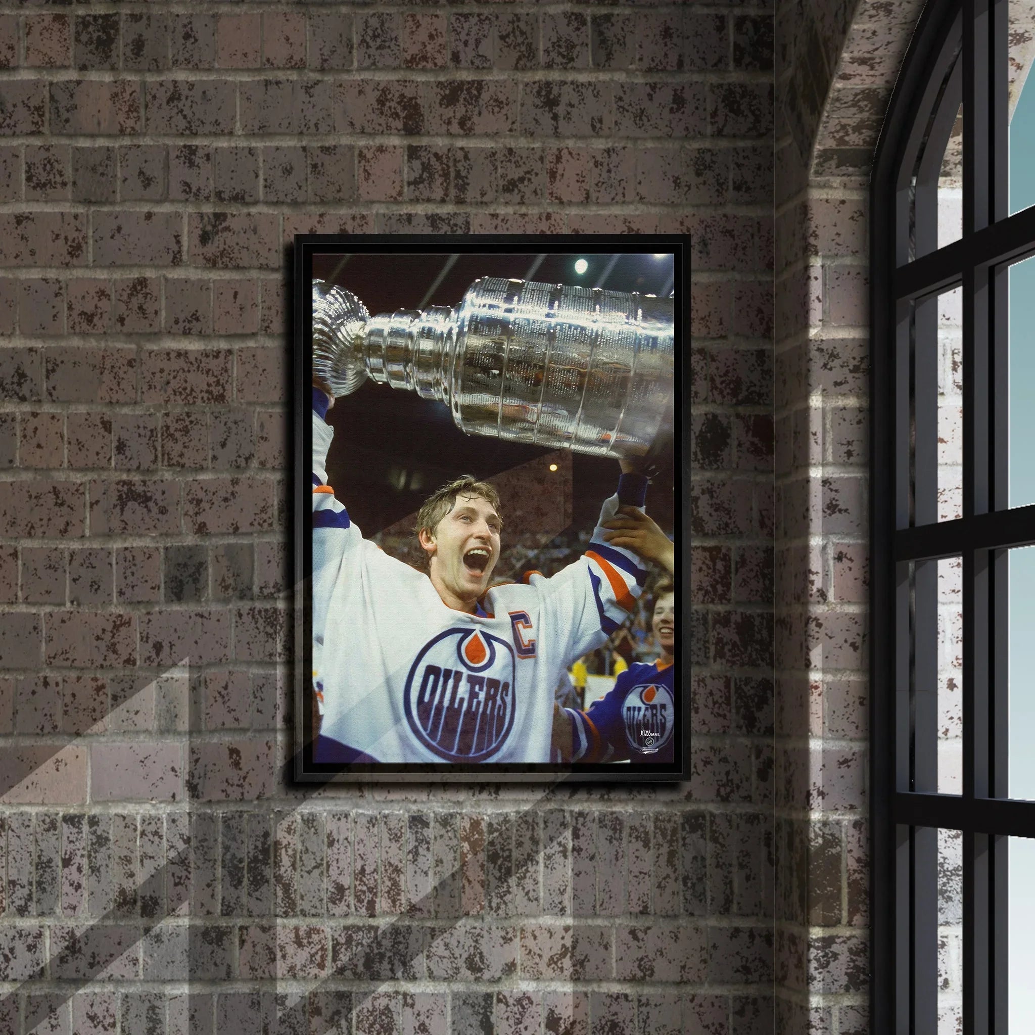 Framed photo of Edmonton Oilers captain holding Stanley Cup on brick wall