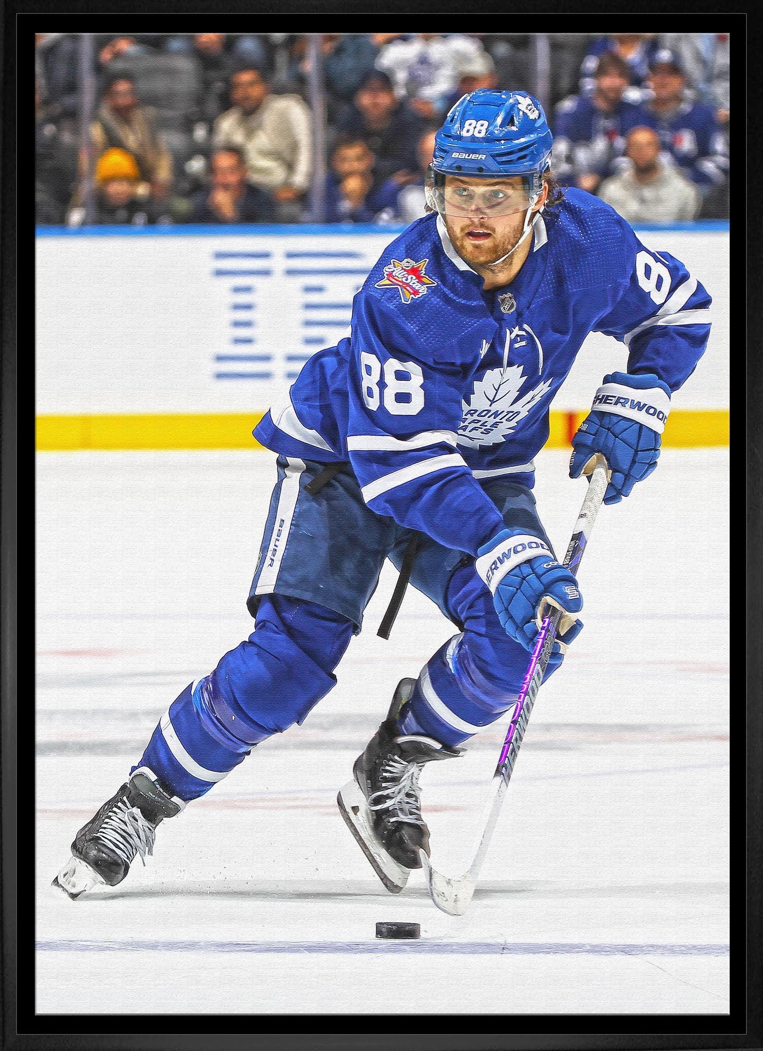 Toronto Maple Leafs hockey player in blue jersey skating with stick and puck on ice rink
