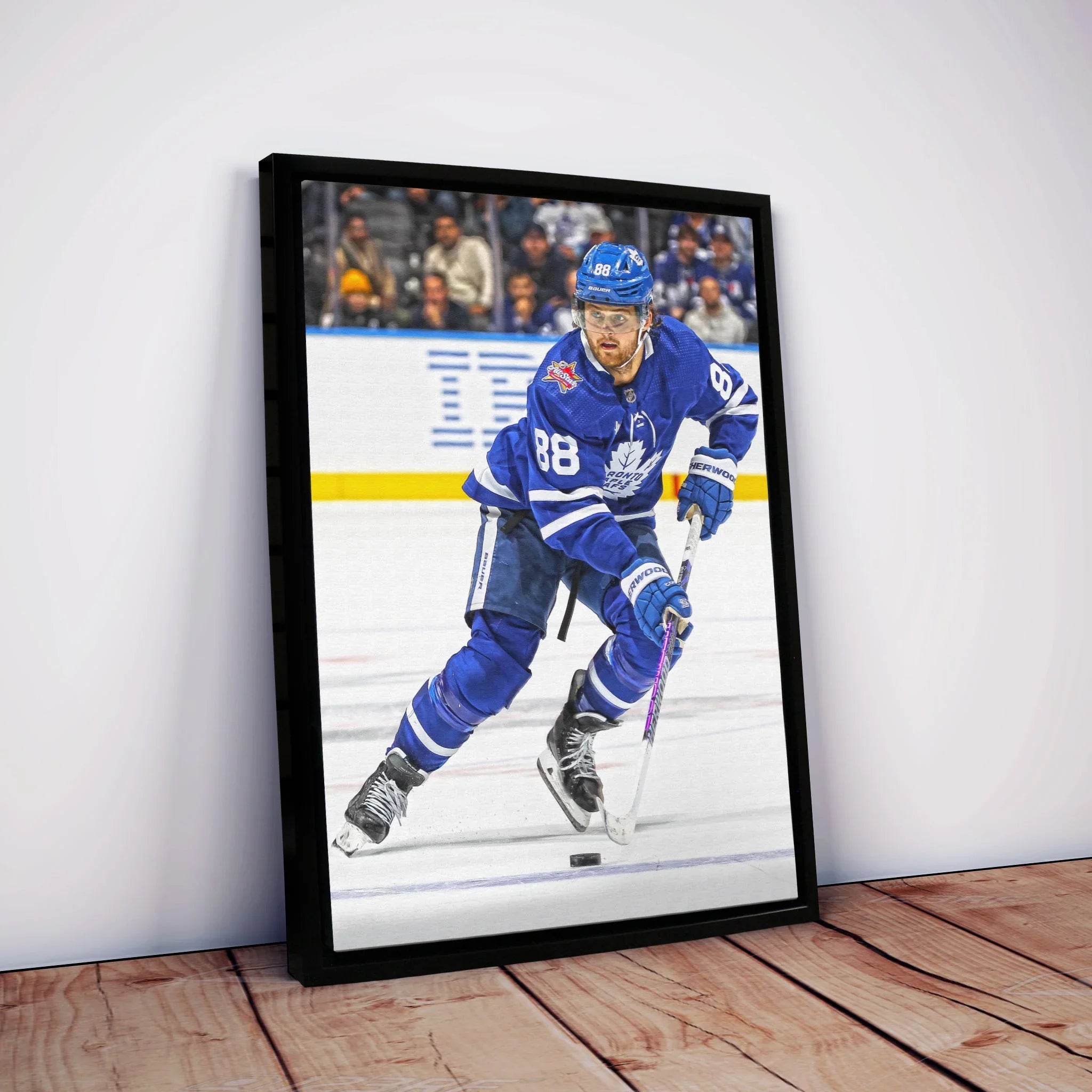 Framed Toronto Maple Leafs hockey player wall art on wooden floor against white wall