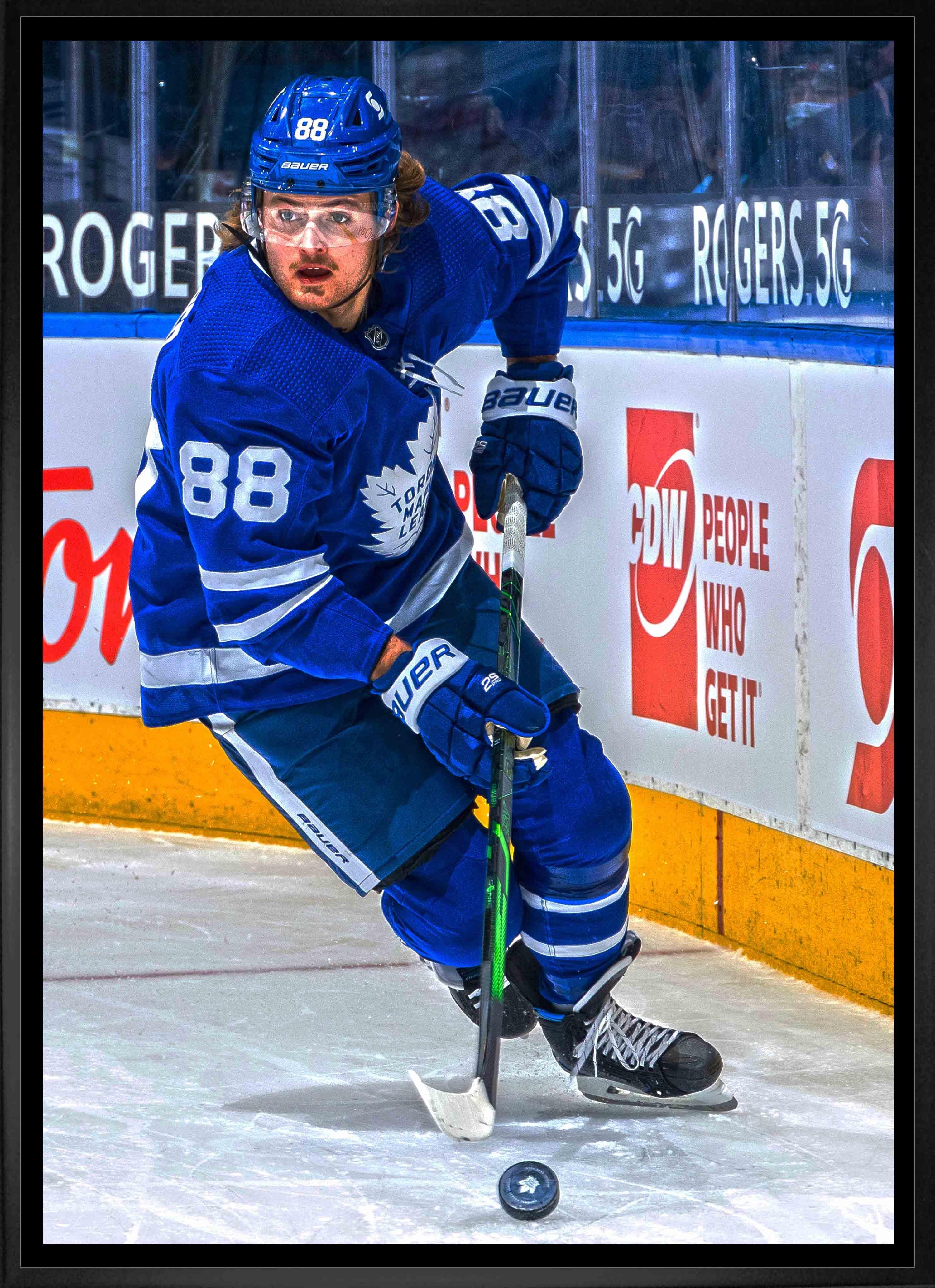 Toronto Maple Leafs hockey player in blue jersey skating with puck on ice rink