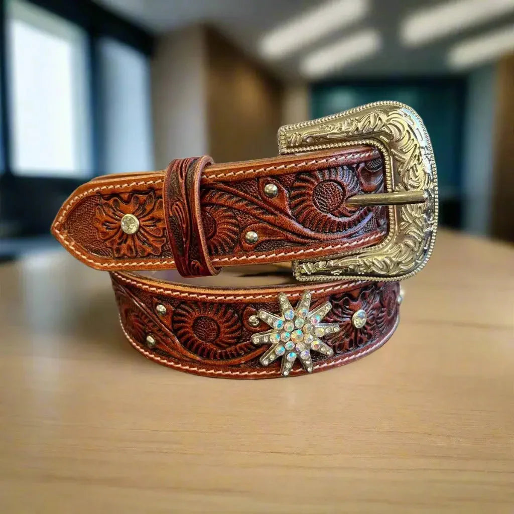 Women's embossed western leather belt with large ornate buckle and rhinestone star on wood table