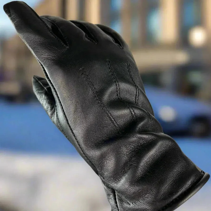 Black women's leather glove with visible stitching, outdoor background