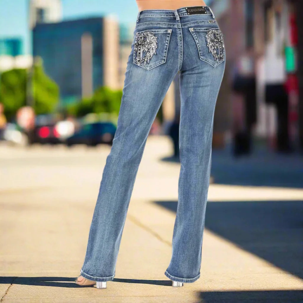 Back view of a woman in blue jeans with embroidered pockets, standing on a city street