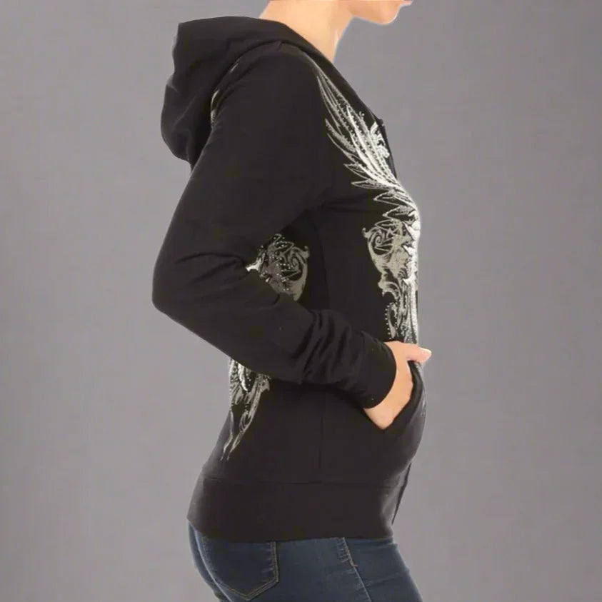Woman wearing black graphic hoodie with silver wing design and blue jeans, side view