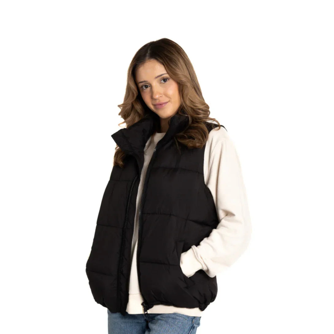 Woman wearing black puffer vest over white sweatshirt, casual winter outfit