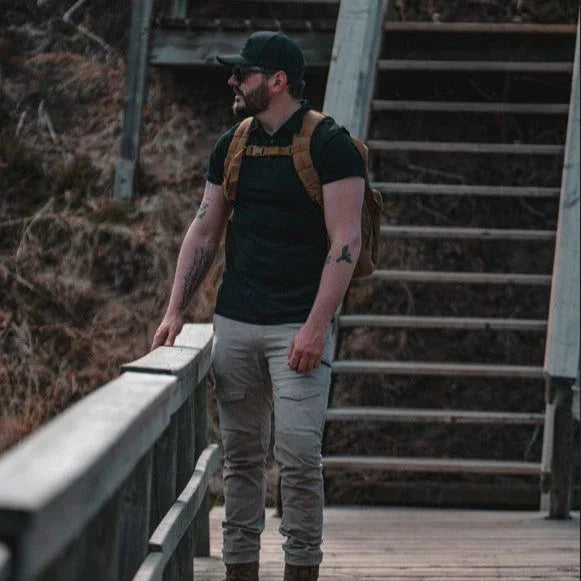 Man wearing black Merino wool golf polo and backpack on wooden outdoor stairs